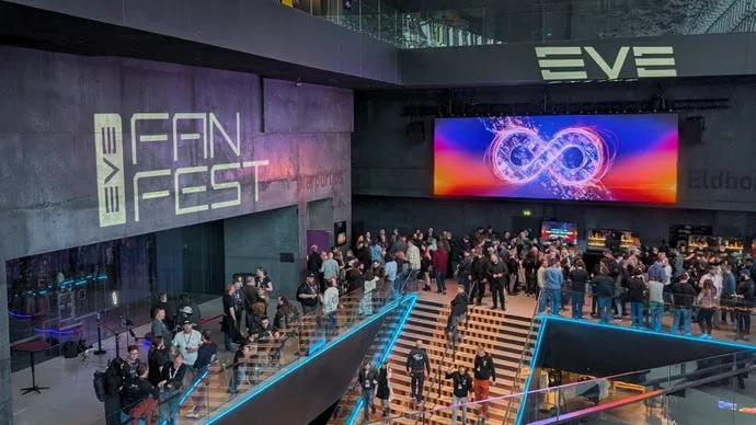 En stor folkmassa på EVE Fanfest, med en stor skärm och EVE-logotyper.