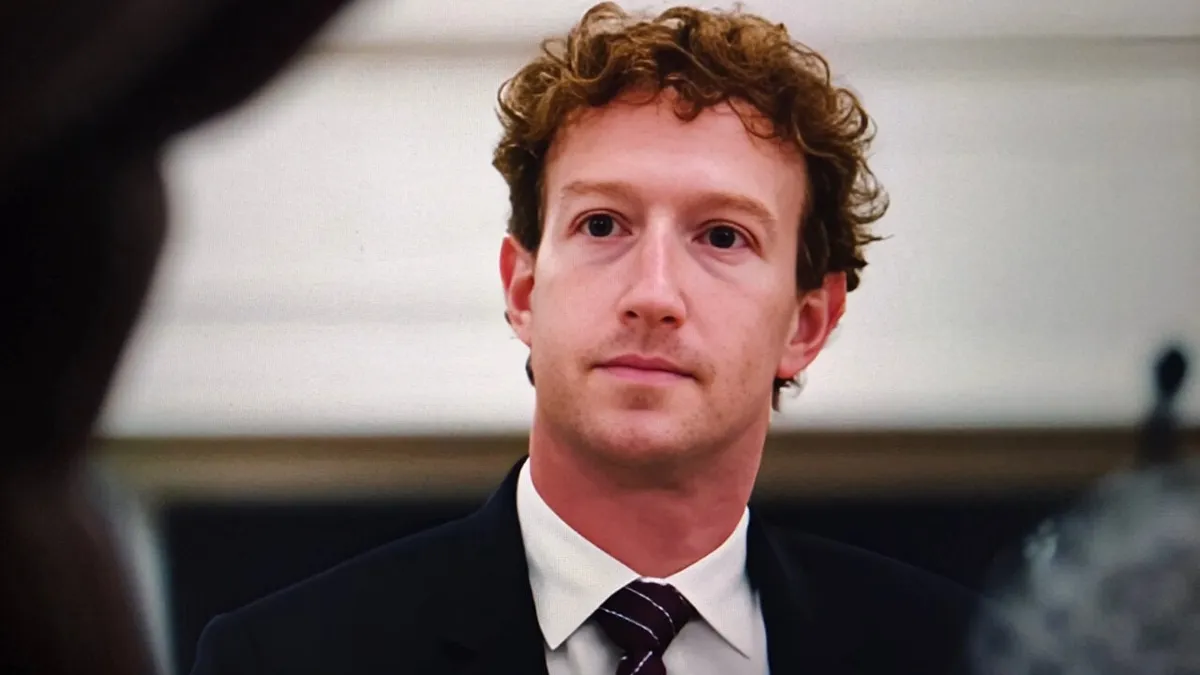 Närbild på Mark Zuckerberg i kostym och slips, med lockigt hår.