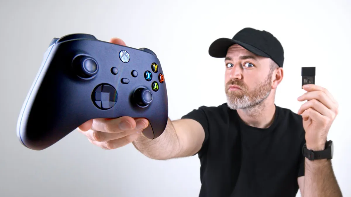 En man håller en Xbox-kontroll i ena handen och ett expansionskort i den andra.